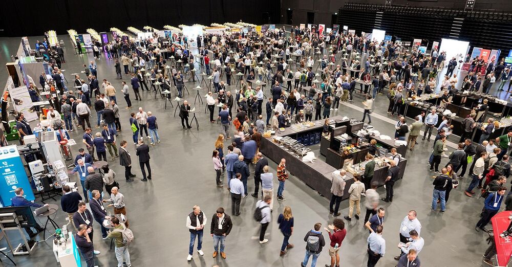 Blick von oben auf die Aussteller und Hunderte Forumsteilnehmende in einer Forumspause in der neuen Festhalle von Bernexpo. 